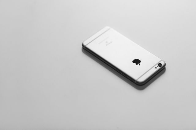 Silver smartphone placed on a plain white surface, highlighting its sleek and modern design. Perfect for technology reviews, advertisements, blog posts about smartphones, or articles on modern gadgets.