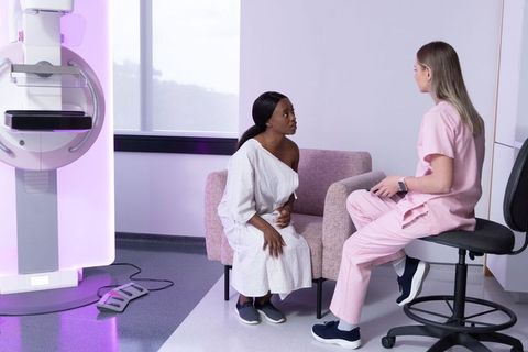 Woman receiving mammogram consultation with radiology technologist in modern clinic