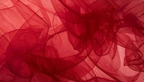 Crimson tulle layers draping over backlit surface abstract textile background