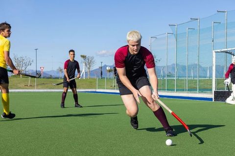 Vibrant Play in Outdoor Field Hockey Match on Sunny Day