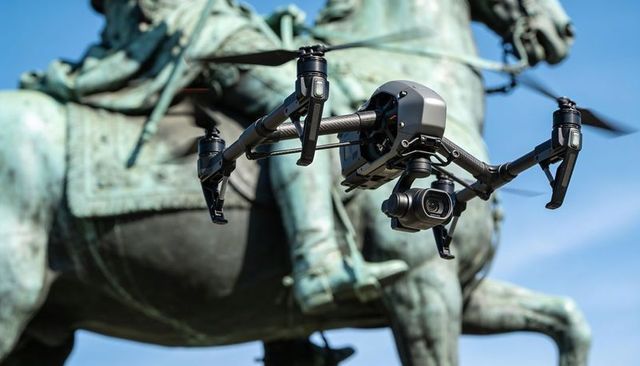 Autonomous filming drone hovering near historic equestrian statue with gimbal camera