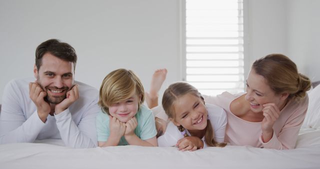 Happy Family of Four Relaxing on Bed in Bright Room - Download Free Stock Images Pikwizard.com