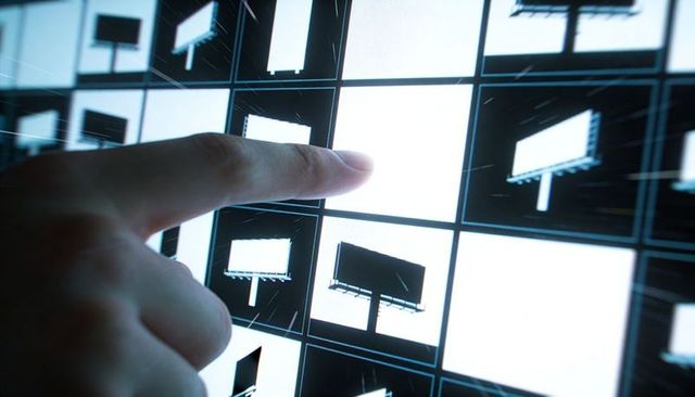 Pressing fingertip selecting central tile on backlit touchscreen grid with billboard icons