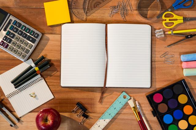 Open diary surrounded by various stationery items on a wooden table. Ideal for back-to-school themes, office organization, educational materials, and creative workspace concepts.