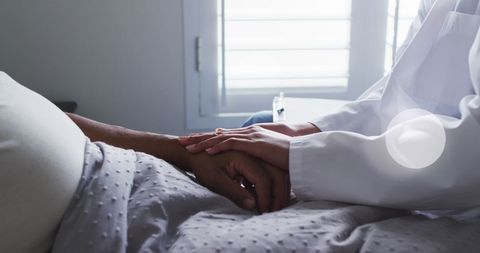 Supportive Doctor and Patient Holding Hands in Hospital Room