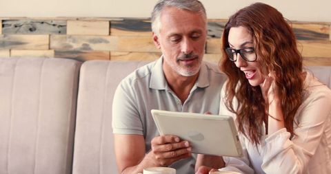 Middle-Aged Couple Enthusiastically Engaging with Tablet Technology