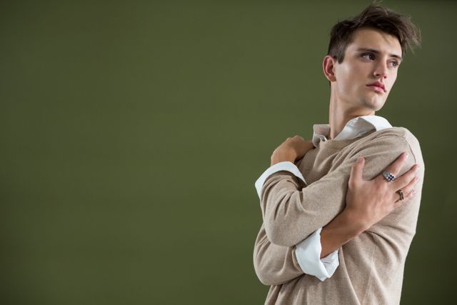 Androgynous man touching his body against green background