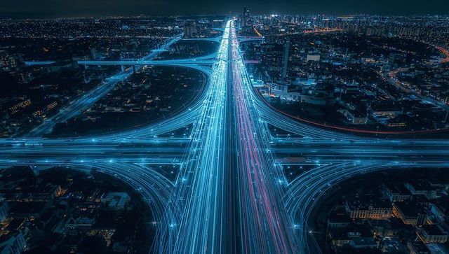 Neon light trails flowing along futuristic aerial multilane highway through night city