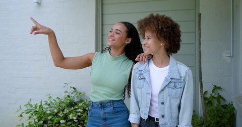 African american friends pointing and smiling on porch garden casual denim lifestyle