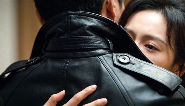 Couple embracing in close leather jacket hug showing tender intimacy and fashion detail