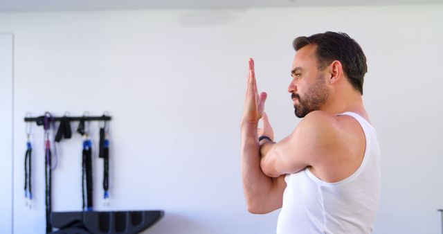 Man practicing yoga pose in bright indoor space, engaging in physical wellness and mindfulness. Home exercise and flexibility training concept, suitable for promoting health, wellness programs, and stress relief activities.