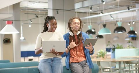 African American colleagues collaborating in modern coworking lounge with laptop and tablet