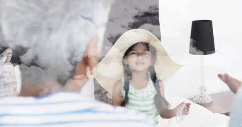 Dreamlike bedroom bonding moment: little girl wearing straw hat holding beads