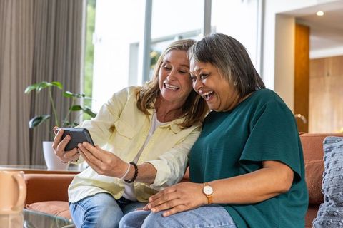 Senior female friends sharing a joyful moment with smartphone