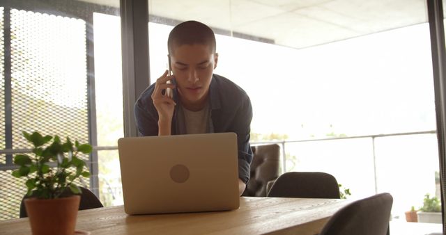 Young Professional Working at Indoor Office on Laptop while Talking on Phone - Download Free Stock Images Pikwizard.com