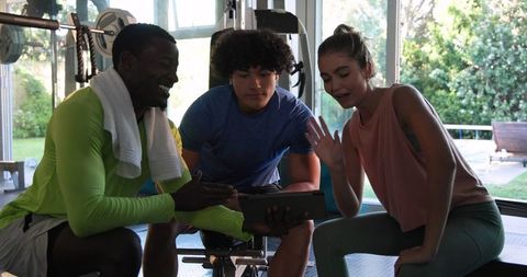 Group viewing workout tutorial online in glass-walled gym