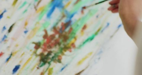 African american woman painting vibrant abstract canvas with fine brush in artist studio