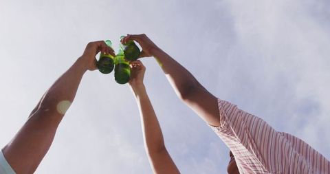 Hands Toasting with Beer Bottles at Outdoor Celebration