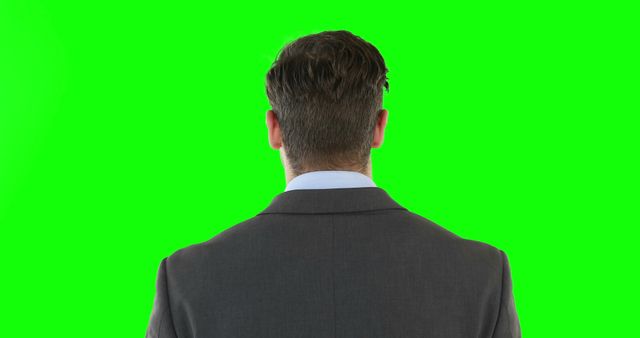 A Caucasian businessman is seen from behind against a green screen background, with copy space. His professional attire suggests a corporate or formal work environment, ready for digital editing.
