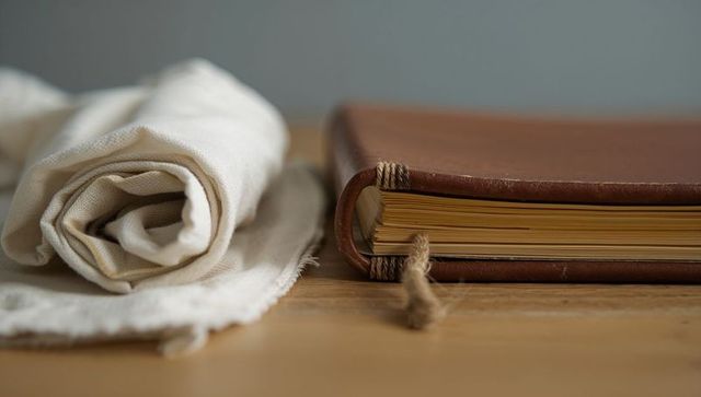 Vintage leather journal with frayed twine and linen closeup on wood table rustic sketchbook