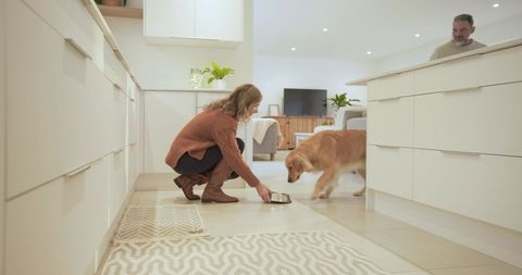 Woman Feeding Golden Retriever in Modern Home Kitchen
