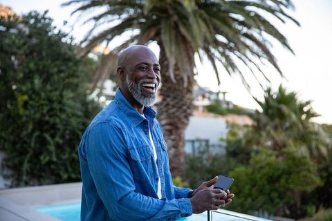 Senior Man Enjoying Leisure Time on Balcony with Smartphone
