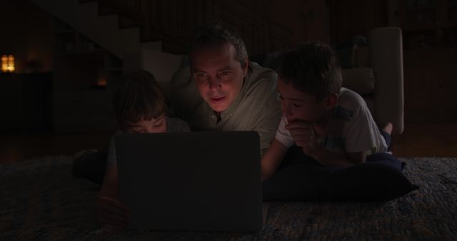 Father and Sons Watching a Laptop Screen Together in Dim Light - Download Free Stock Images Pikwizard.com