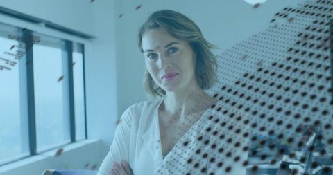 Confident businesswoman standing by office window with modern dotted glass decal