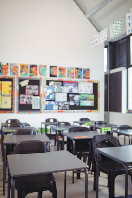 Empty classroom with rows of desks and chairs, colorful bulletin boards on walls. Ideal for educational content, school brochures, academic articles, and teaching materials.
