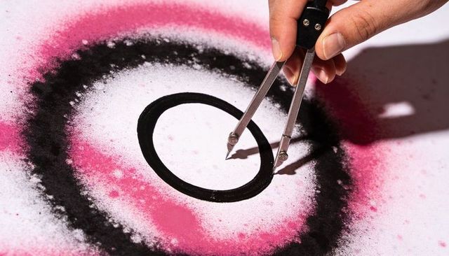 Precision compass drawing concentric circles with pink spray pigment halo for design
