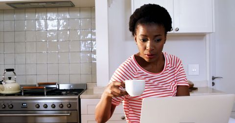 Focused Woman Using Laptop While Drinking Coffee in Modern Kitchen - Download Free Stock Images Pikwizard.com