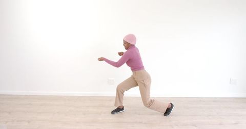 Woman in pink sweater dancing on wooden floor