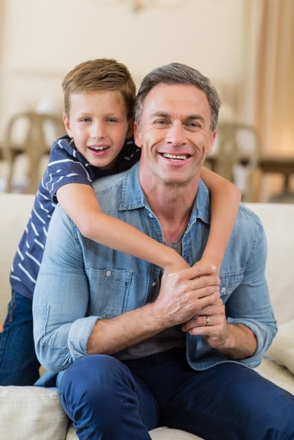 Father and son sharing a joyful moment in a cozy living room. Ideal for use in family-oriented advertisements, parenting blogs, and lifestyle magazines. Perfect for illustrating themes of family bonding, love, and happiness.