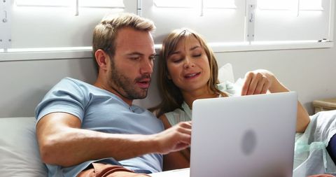 Couple Relaxing at Home Engaged in Laptop Discussion