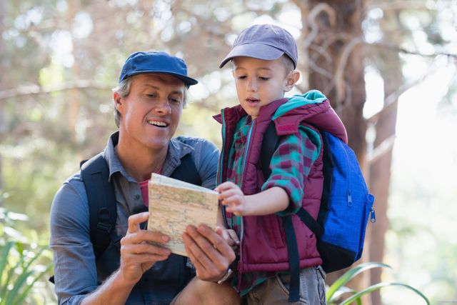 Mature man and boy reading map in forest