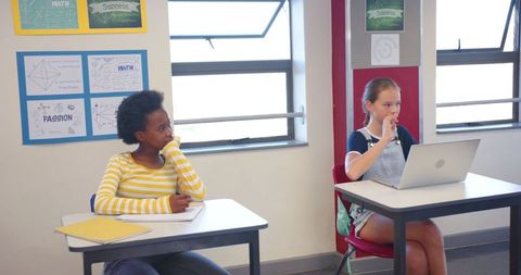 Diverse female classmates engaged in school work in classroom