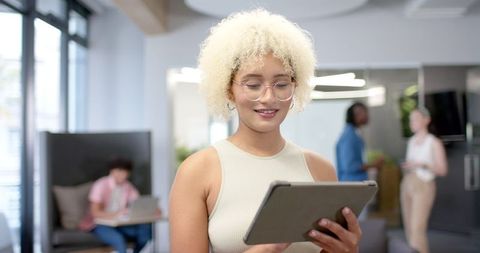 Confident businesswoman engaging with digital tablet in modern office setting