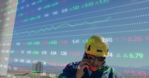 Field engineer communicating by phone with stock market overlay and energy analytics