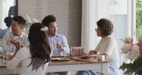 Happy friends gathering around dining table at home