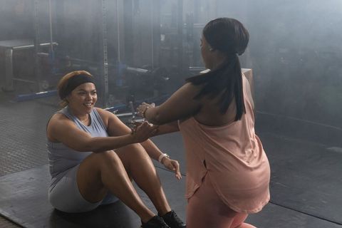 African american women doing partner sit-ups, motivated training session in gym