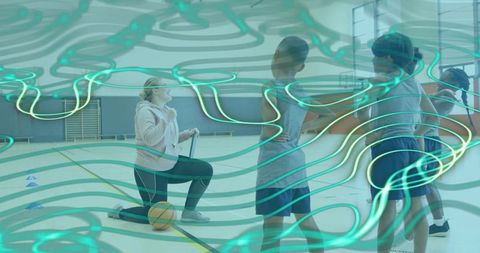Kneeling coach guiding youth basketball drills in gymnasium, children practicing teamwork