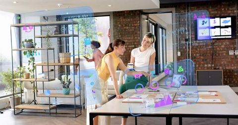 Two women collaborating with ar analytics and holographic charts in startup coworking office