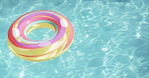 Colorful inflatable ring floating in sparkling swimming pool
