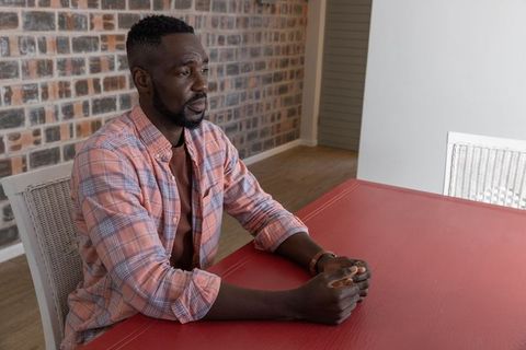 Mature Man Contemplating at Red Table Indoor Rustic Setting