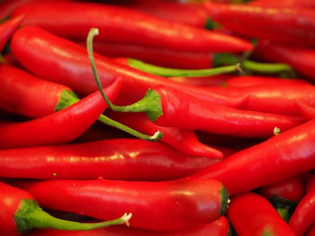 Close-up view of fresh red chili peppers. The vibrant colors signify hot and spicy flavors. Ideal for culinary blogs, food market advertisements, and organic produce promotions. Perfect for use in recipes, cooking guides, and grocery store posters looking for eye-catching visuals.