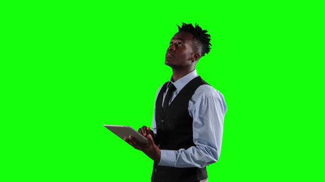 An African American businessman in business attire is using a tablet in a green screen environment, perfect for professional settings and technology-related content. Ideal for depicting scenes of business, tech usage, or marketing materials showcasing individuals in executive roles. Green screen allows for versatile background changes for custom applications.