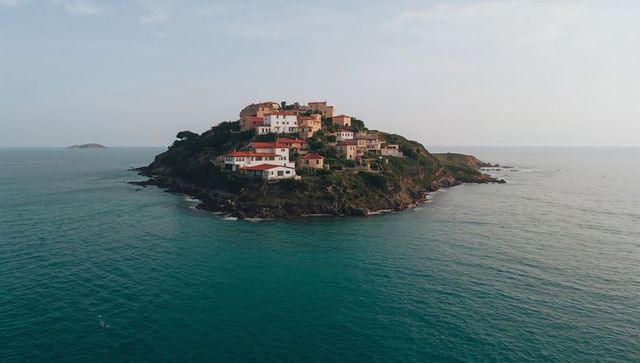 Perching terracotta village on rocky islet surrounded by calm turquoise sea