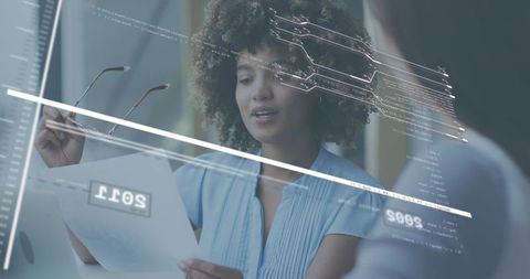 Female professional reviewing document with holographic ui overlay during team collaboration