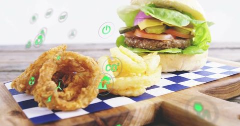Plant-based cheeseburger with onion rings and floating eco icons for sustainable dining