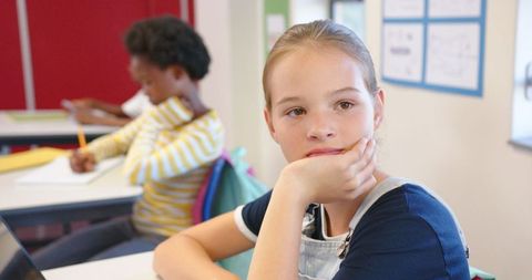 Inquisitive schoolgirl daydreaming in classroom
